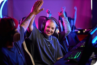 Een groep enthousiaste gamers met een koptelefoon viert een overwinning en geeft elkaar high fives in een met neon verlichte ruimte, waarbij ze teamgeest en vreugde uitstralen.